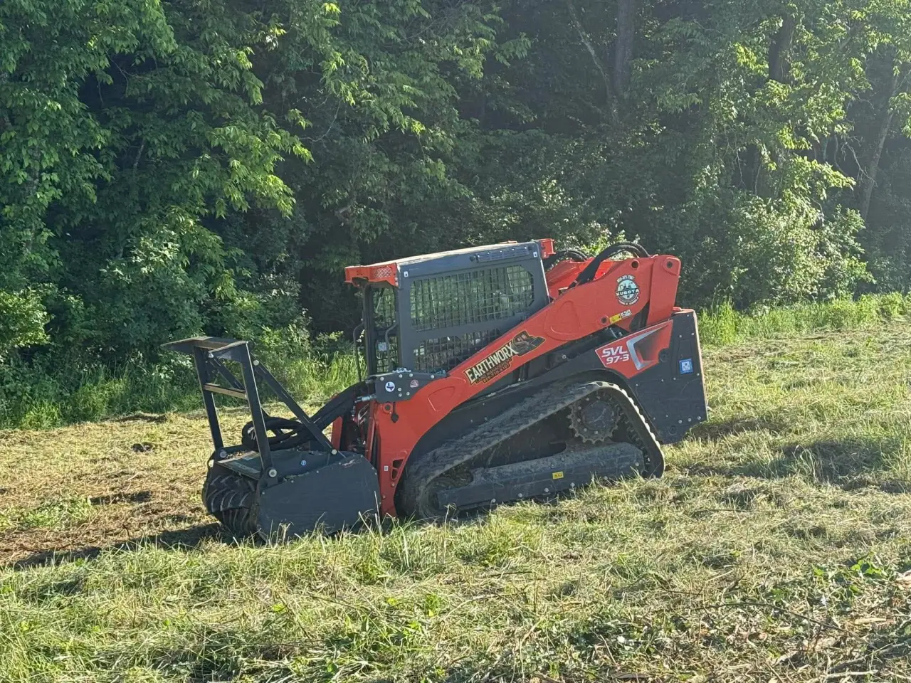 EarthWorx Kubota SVL97-3 compact track loader with forestry mulcher attachment at a wooded property in Northern Kentucky